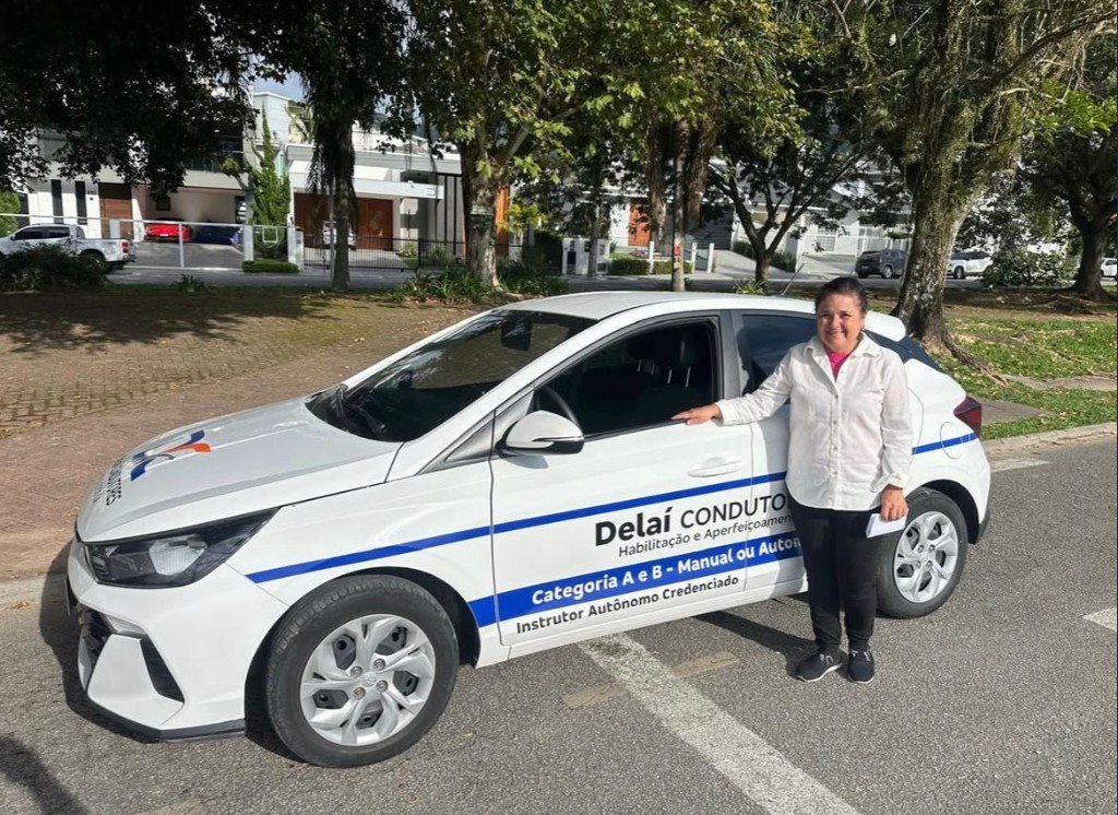 Instrutora ao lado do carro com identidade visual Delaí Condutores